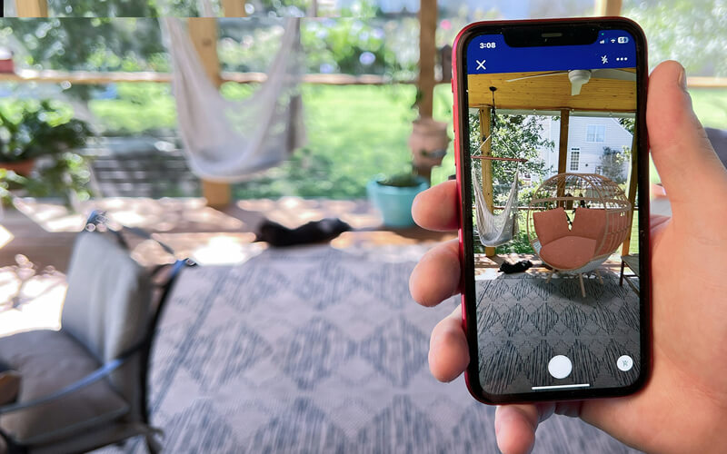 Person holding phone looking at a potential chair option through Lowe's AR visualizer