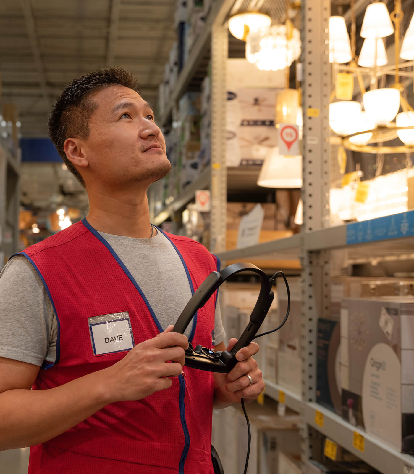 Lowes Home Improvement associate in lighting aisle holding a MagicLeap2 headset to view the digital twin
